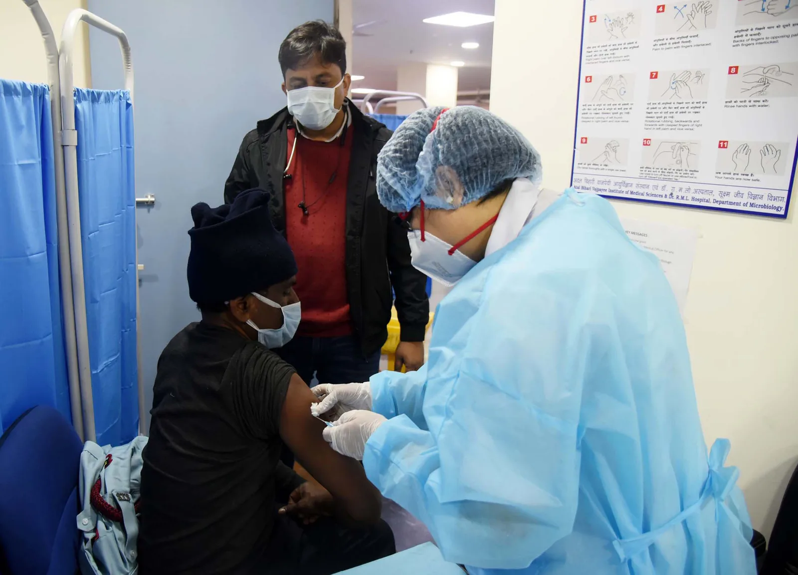 Health workers administer a COVID-19 vaccine at Dr. Ram Manohar Lohia Hospital, New Delhi, on 16 January 2021
